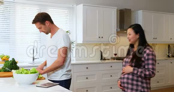 孕妇在切菜时与男子交谈视频的预览图