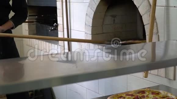 一个年轻的披萨师在餐厅的厨房准备披萨厨师从暖气里拿出准备好的披萨视频的预览图