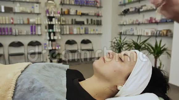 女人美容师把奶油面罩涂在脸上面部的机械清洁视频的预览图