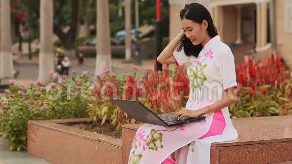 穿着国装的漂亮亚洲女孩坐在大街上手提电脑视频的预览图
