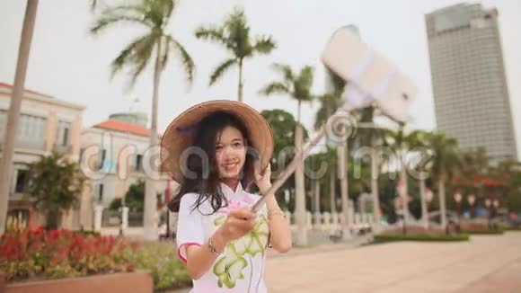 穿着国装的女孩在摩天大楼的背景下在岘港市中心自拍白色电话视频的预览图