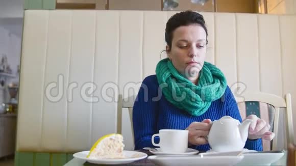 美丽的女人把茶从茶壶里倒进咖啡馆的杯子里视频的预览图