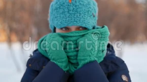 美丽的女人用围巾躲在冬天的公园里视频的预览图