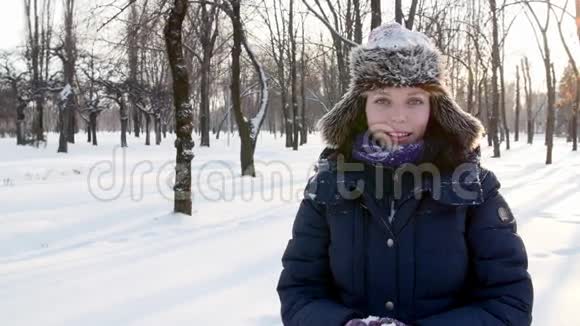 女人把雪洒在自己身上在冬天的公园里微笑着视频的预览图