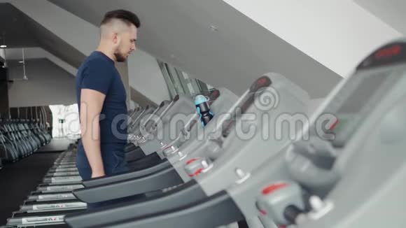 运动服的年轻人在健身房跑步机上跑步开始准备训练锻炼视频的预览图