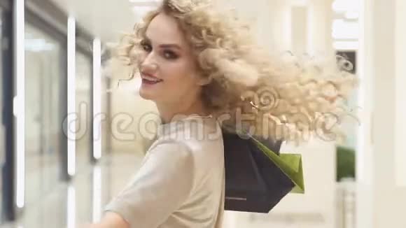 漂亮的女人在商场里拿着购物袋转过身慢动作快乐的女孩用他们的购买视频的预览图