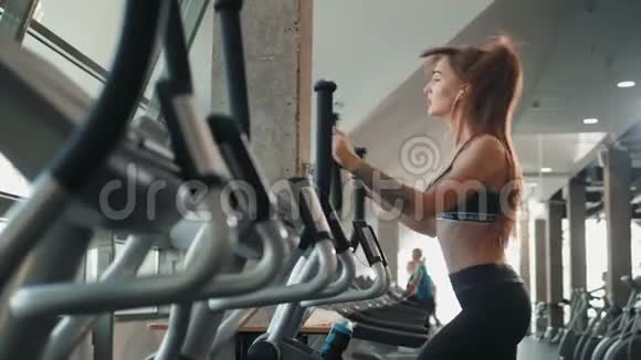 体育运动美丽的黑发健身女子在有氧运动机上锻炼健身女子训练双手腿走路视频的预览图