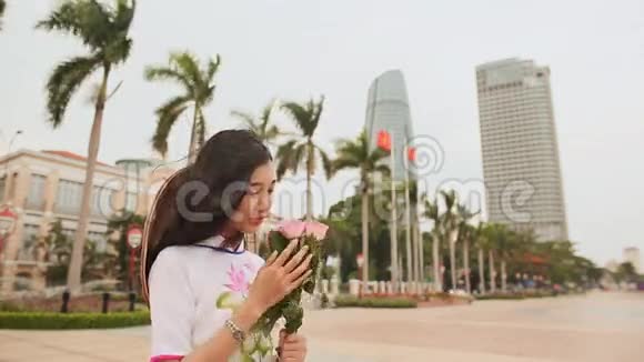 越南女孩穿着民族服装在岘港市区摩天大楼的背景下摆姿势视频的预览图