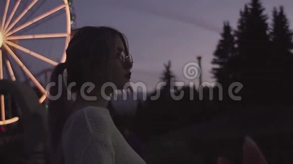 穿着复古眼镜的漂亮年轻女人在游乐园视频的预览图