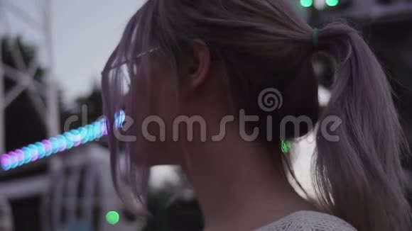 在游乐园里戴着圆眼镜的马尾辫的漂亮年轻女人视频的预览图