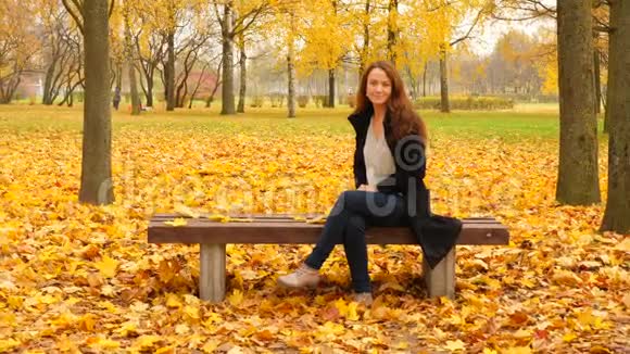 坐在公园里的黄枫叶妇女的肖像视频的预览图