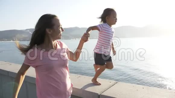 年轻的母亲和小女儿牵着手跑着笑着笑着视频的预览图