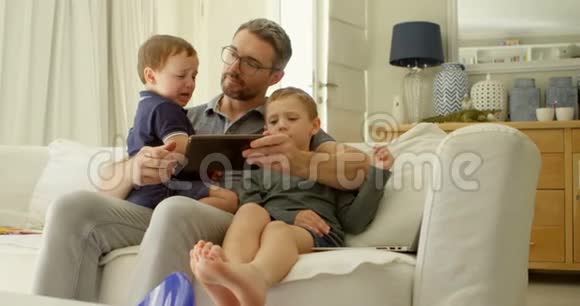 爸爸和孩子们在沙发上用数码平板电脑视频的预览图