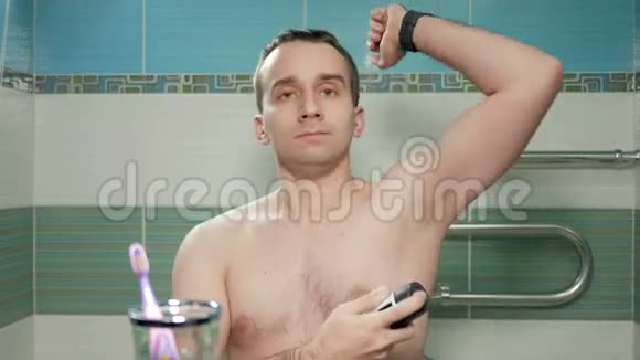 一个年轻有魅力的男人在酒店房间的浴室里喷洒止汗剂他微笑着皱着眉头视频的预览图