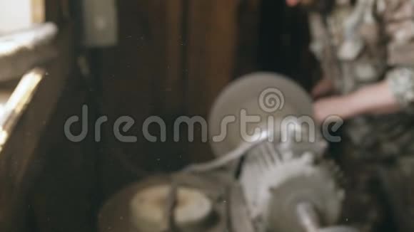 灰尘在模糊的背景上飞舞胡须青年铁匠在磨床上手工打磨金属刀视频的预览图