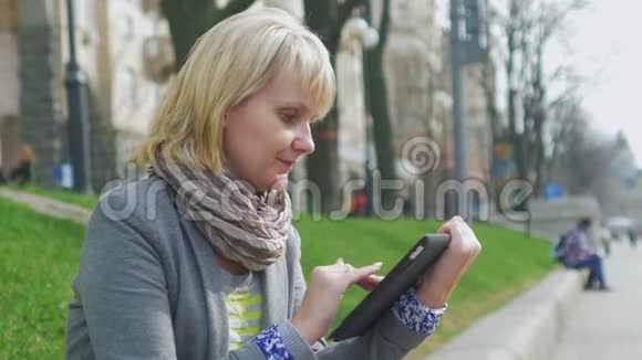 年轻女子在公园里休息享受数码平板电脑视频的预览图