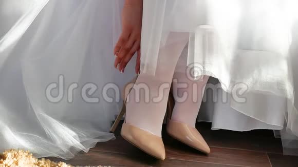 穿着白色连衣裙的新娘穿上鞋子来伸直手指婚礼概念节日室内生活视频的预览图