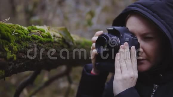 女孩摄影师走过秋天的森林拍摄大自然的照片电影镜头慢动作视频的预览图
