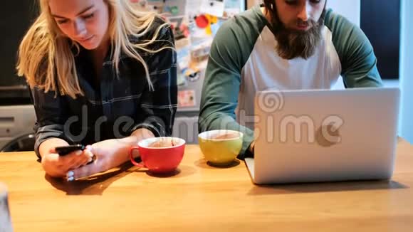 一对夫妇在厨房用笔记本电脑和手机视频的预览图