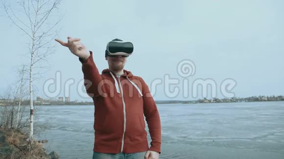 一个人站在一个春天的池塘旁边用虚拟现实眼镜视频的预览图