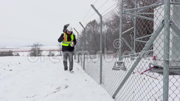 拿着雪铲的工人走在栅栏附近开始喝茶视频的预览图