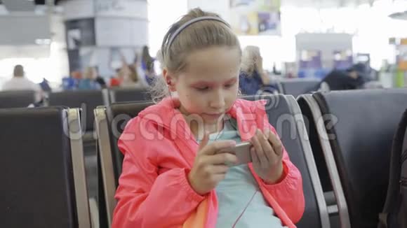 在机场大厅玩智能手机的小女孩视频的预览图