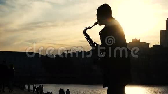 街头音乐家演奏萨克斯风日落剪影视频的预览图