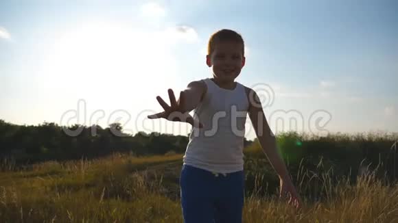 快乐的小男孩伸出的手在镜头后的田野里跑试图抓住它微笑男孩子视频的预览图