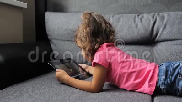 小女孩躺在沙发上用平板电脑小女孩躺着玩平板电脑视频的预览图
