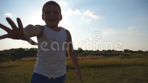快乐的小男孩伸出的手在镜头后的田野里跑试图抓住它微笑男孩子视频的预览图