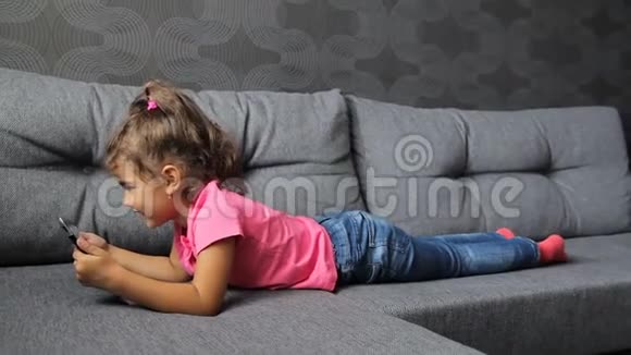 小女孩躺在沙发上用平板电脑小女孩躺着玩平板电脑视频的预览图