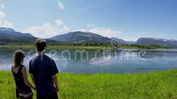 一对夫妇观看美丽的湖泊环绕着4k山脉视频的预览图