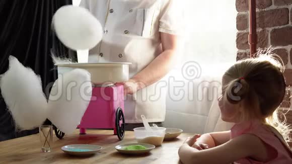 一个男厨师在一台特殊的机器上为一个可爱的小女孩做棉花糖视频的预览图