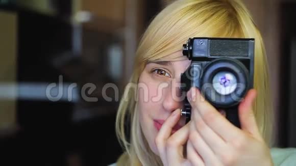 有着不同眼睛的金发美女在旧的复古相机上拍摄异色视频的预览图
