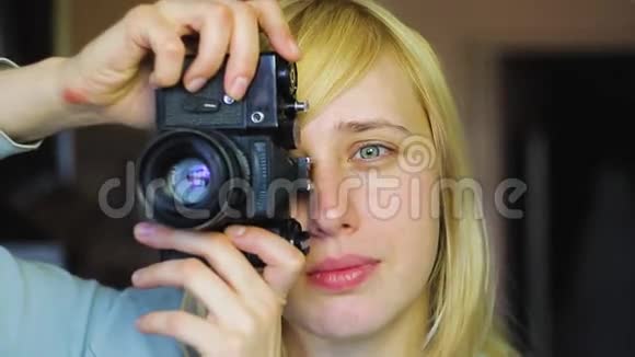 有着不同眼睛的金发美女在旧的复古相机上拍摄异色视频的预览图