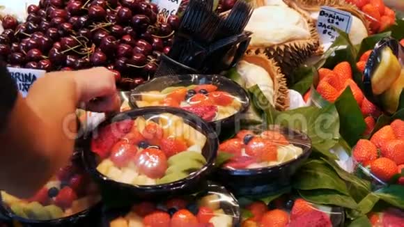 许多不同的热带水果在市场柜台上人们选择水果在集市或水果市场西班牙巴塞罗那视频的预览图