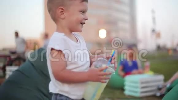 夏天漂亮的小男孩在公园里玩得很开心拿着一杯吸管笑着视频的预览图