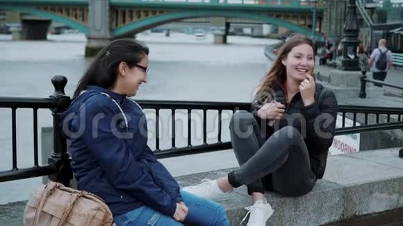 两个女孩坐在泰晤士河畔闲聊视频的预览图