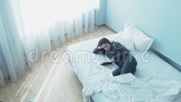 一个年轻可爱的女人穿着睡衣早上在床上看书在床上看书的漂亮年轻女子视频的预览图