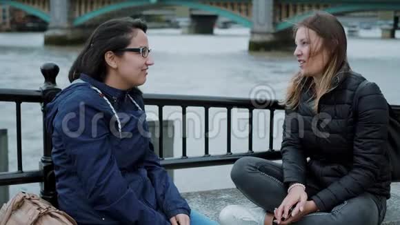 两个女孩坐在泰晤士河畔闲聊视频的预览图