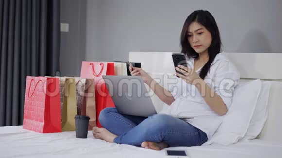 幸福的女人用智能手机上网购物床上有信用卡视频的预览图