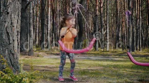 可爱的女孩在森林里玩着五颜六色的秋千视频的预览图