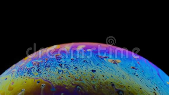 一个肥皂泡的五彩彩虹颜色看起来像一个在黑色背景下孤立的梦幻星球视频的预览图