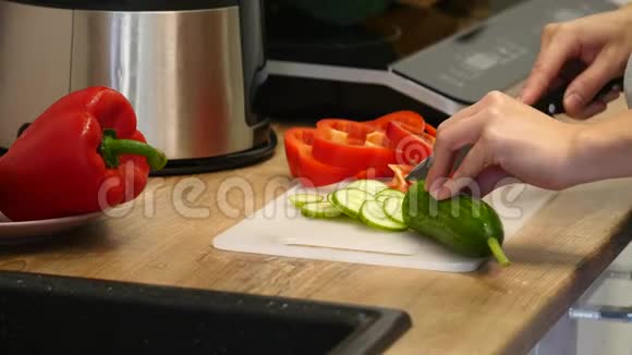 女人切黄瓜雌性手切绿色黄瓜环一把大刀在厨房里木板房子骄傲视频的预览图