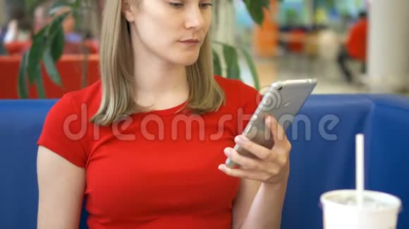 女人坐在咖啡馆里用她的智能手机和朋友聊天吃炸薯条视频的预览图