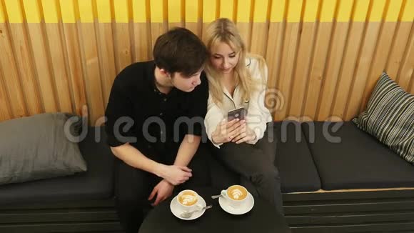 快乐的一对夫妇一起使用智能手机在咖啡馆喝咖啡视频的预览图