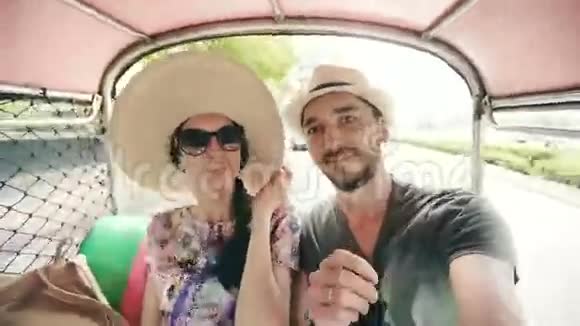 年轻的帅哥戴着帽子女朋友骑着传统的泰国公共汽车在智能手机上自拍夫妇视频的预览图
