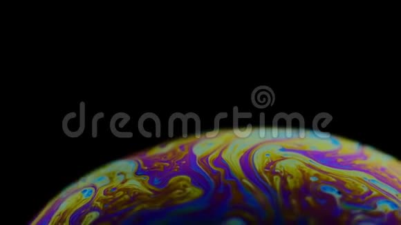 一个肥皂泡的五彩彩虹颜色看起来像一个在黑色背景下孤立的梦幻星球视频的预览图