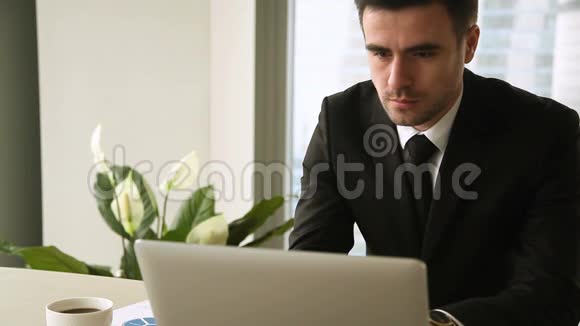 在工作场所工作的认真成功的企业家在笔记本电脑上工作喝咖啡视频的预览图