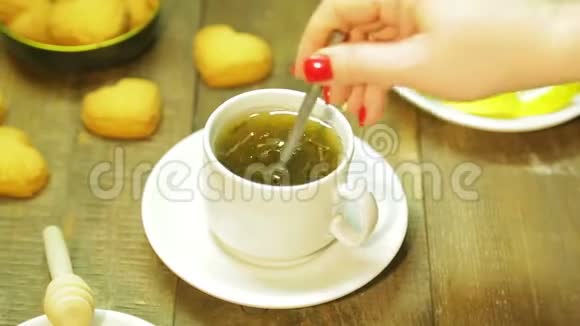 女人在木桌上的白色杯子里搅拌勺子新鲜绿茶视频的预览图